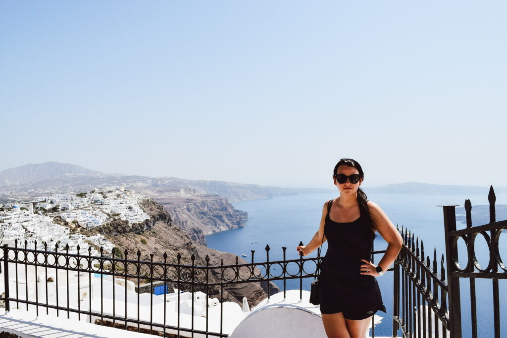 Woman poses by railing in Greece