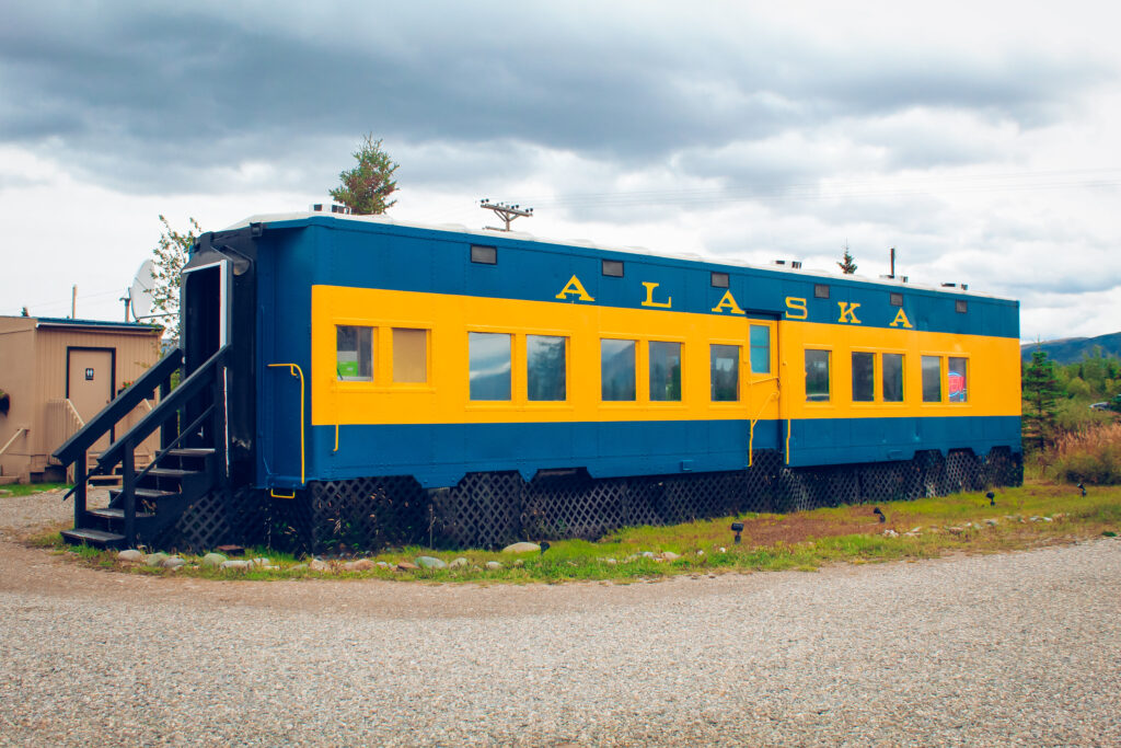 The exterior of a blue and yellow Alaskan train car with.