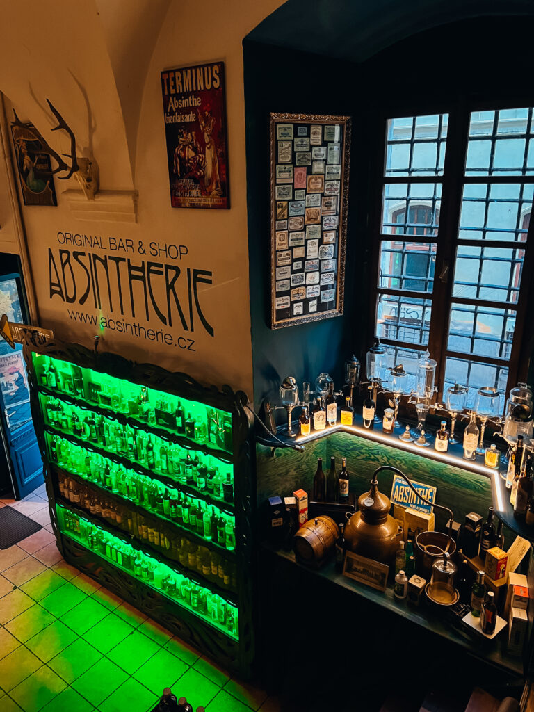 Absintherie​ in green lighting. Shelves with bottles.