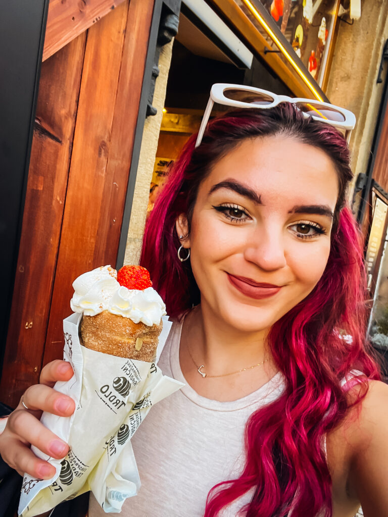 A woman with pink hair holding a pastry.