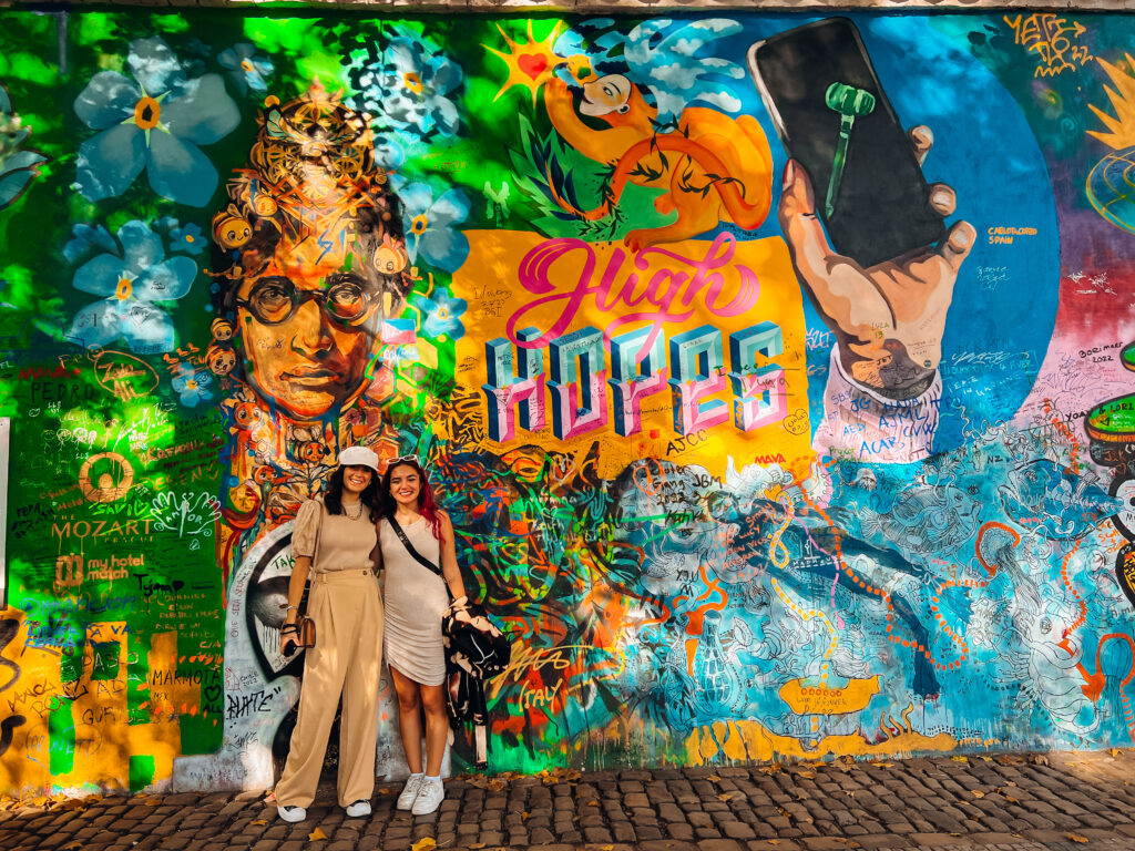 Two women standing in front of the John Lennon Mural.