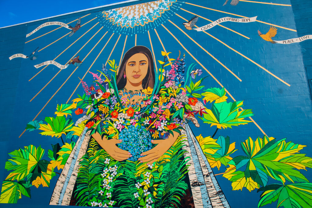 A mural of a woman holding flowers under the sun.
