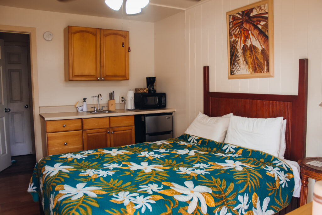 A bed with a floral comforter and a kitchenette