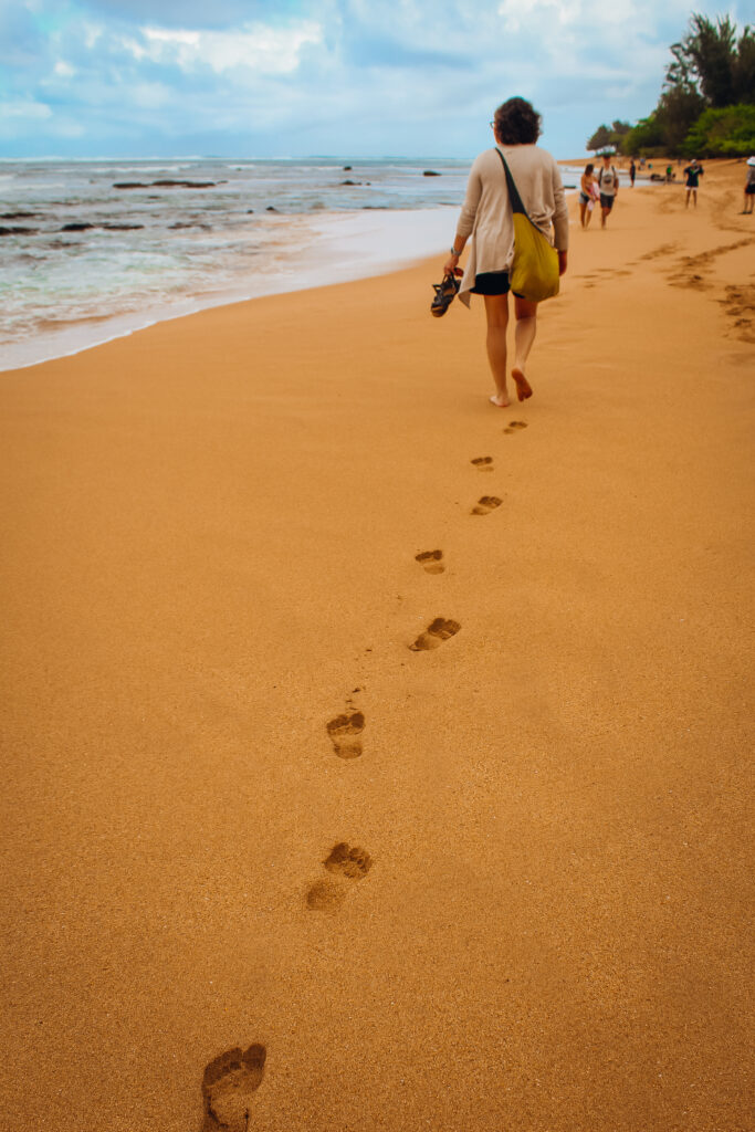 A woman walking along the beach with her footprints in the distance