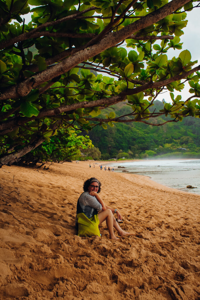 A woman sitting under a tree on the beach