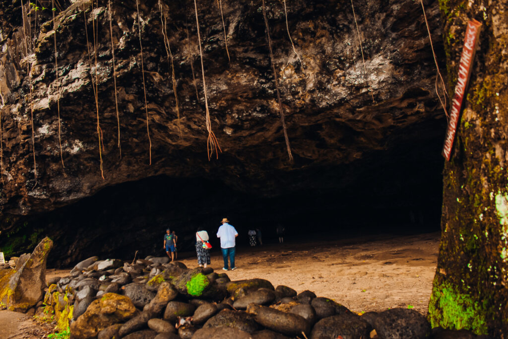 Two people standing in front of a large cave mouth