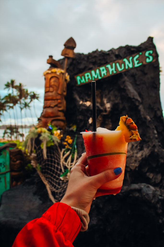 A cocktail in front of a sign that says Mamahune's