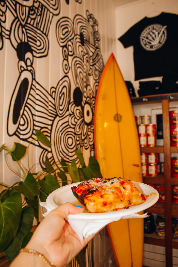 Pizza in front of a surf board.