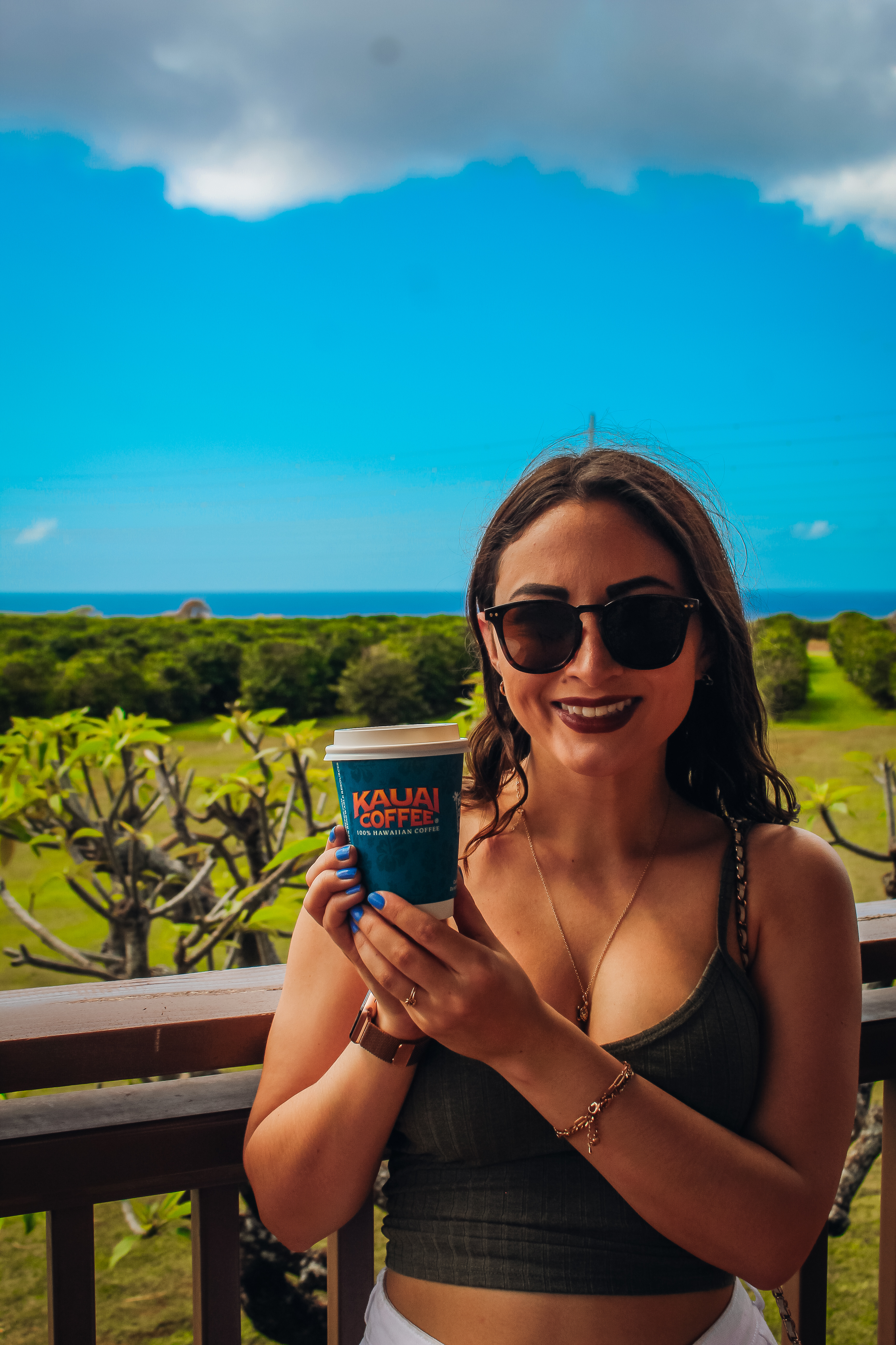 Woman holding coffee cup in front of a view of the ocean.