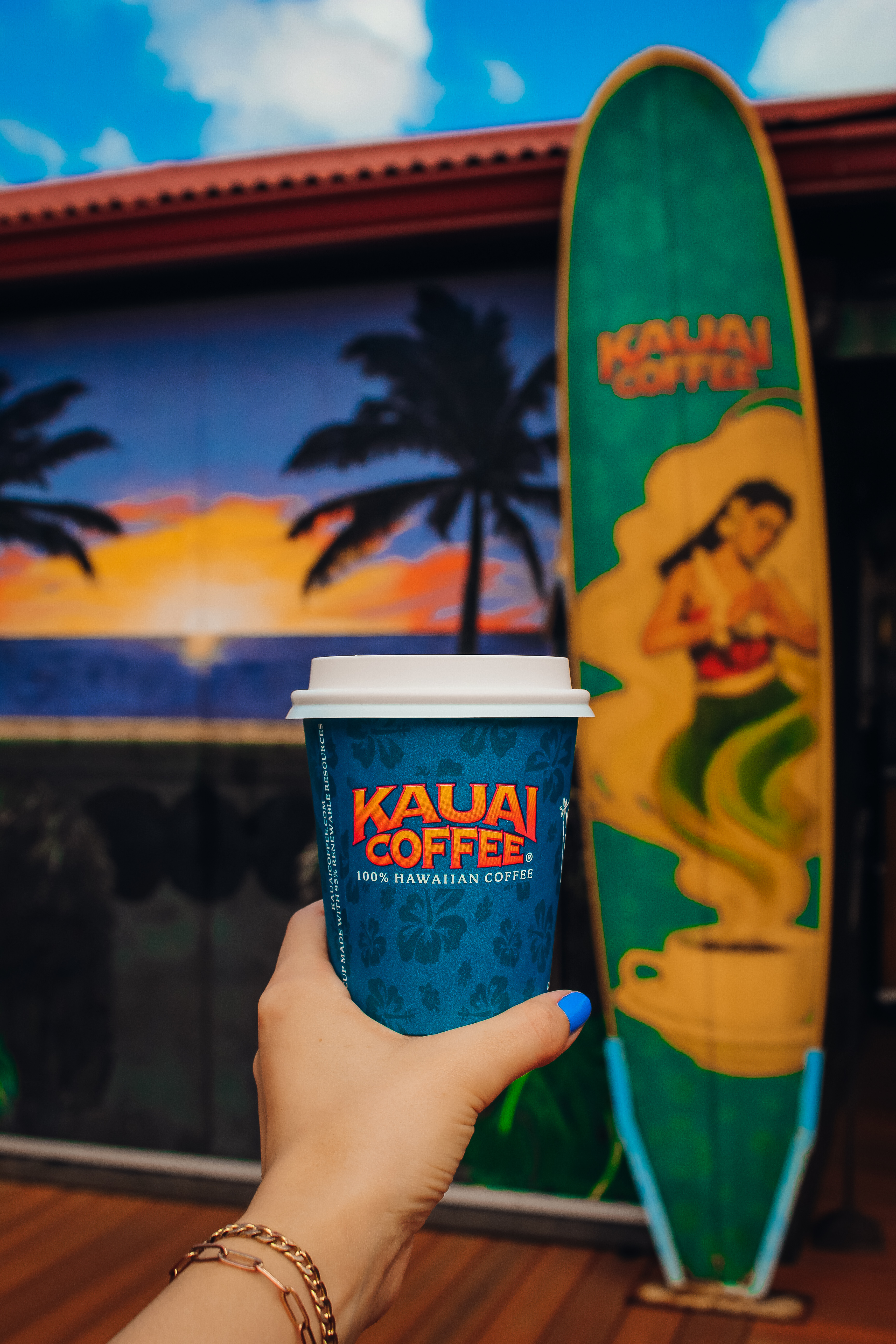 Kauai Coffee cup in front of a surf board.