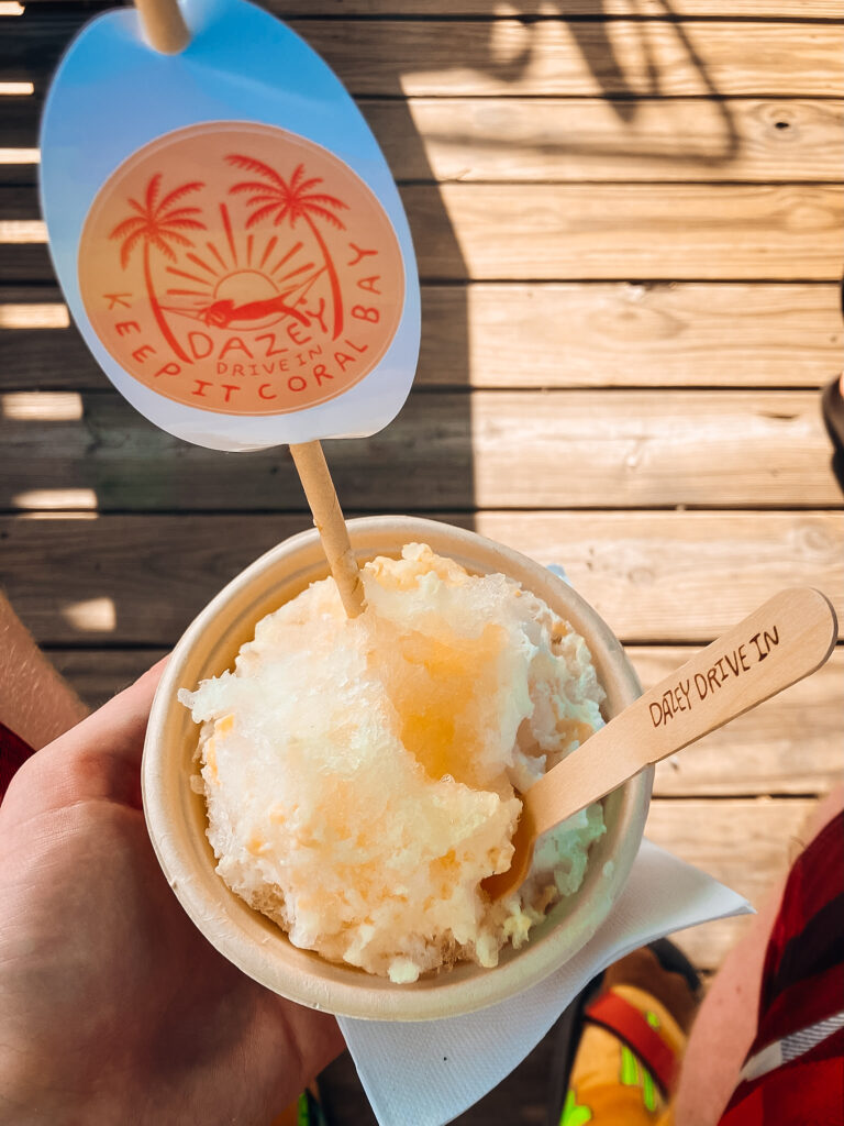 A hand holding a cup of orange shave ice.